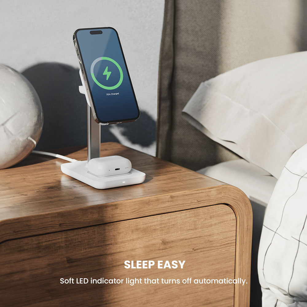 Smartphone on a charging stand with a soft LED indicator light on a wooden nightstand.