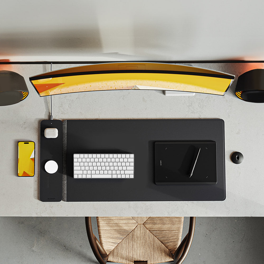 Modern desk setup with a lamp, phone, keyboard, and tablet on a gray surface.