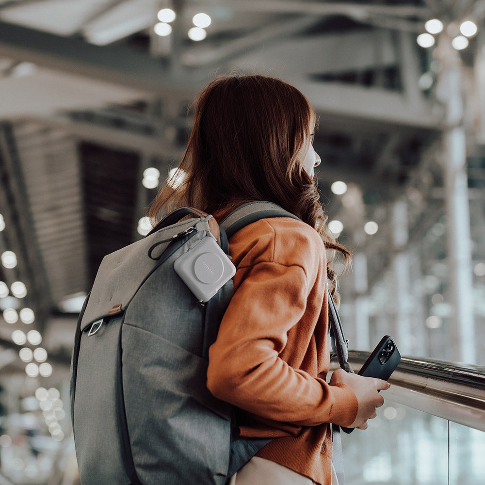 Person with a backpack and suitcase in an airport terminal