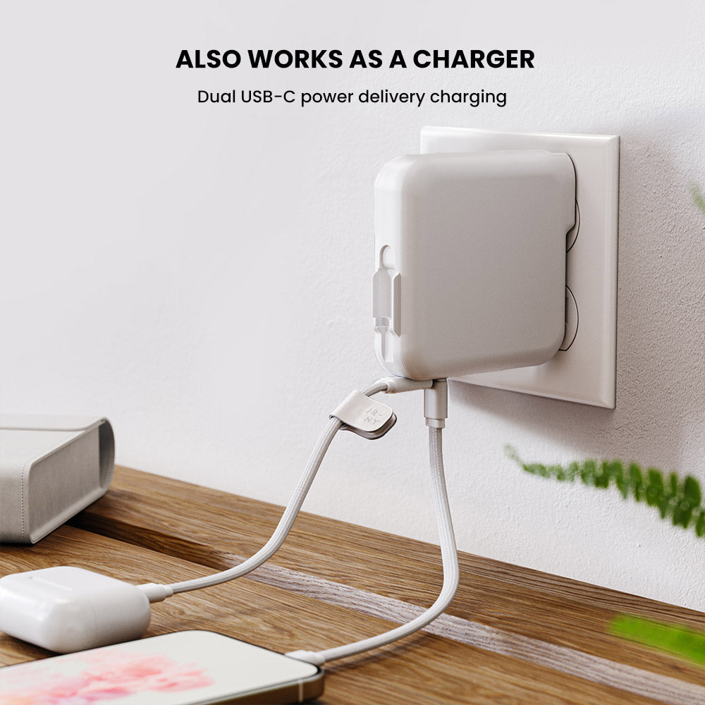 White power adapter with USB-C cable plugged into a wall socket on a wooden surface.