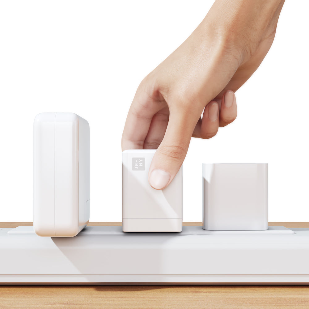 Hand interacting with a white electronic device on a wooden surface