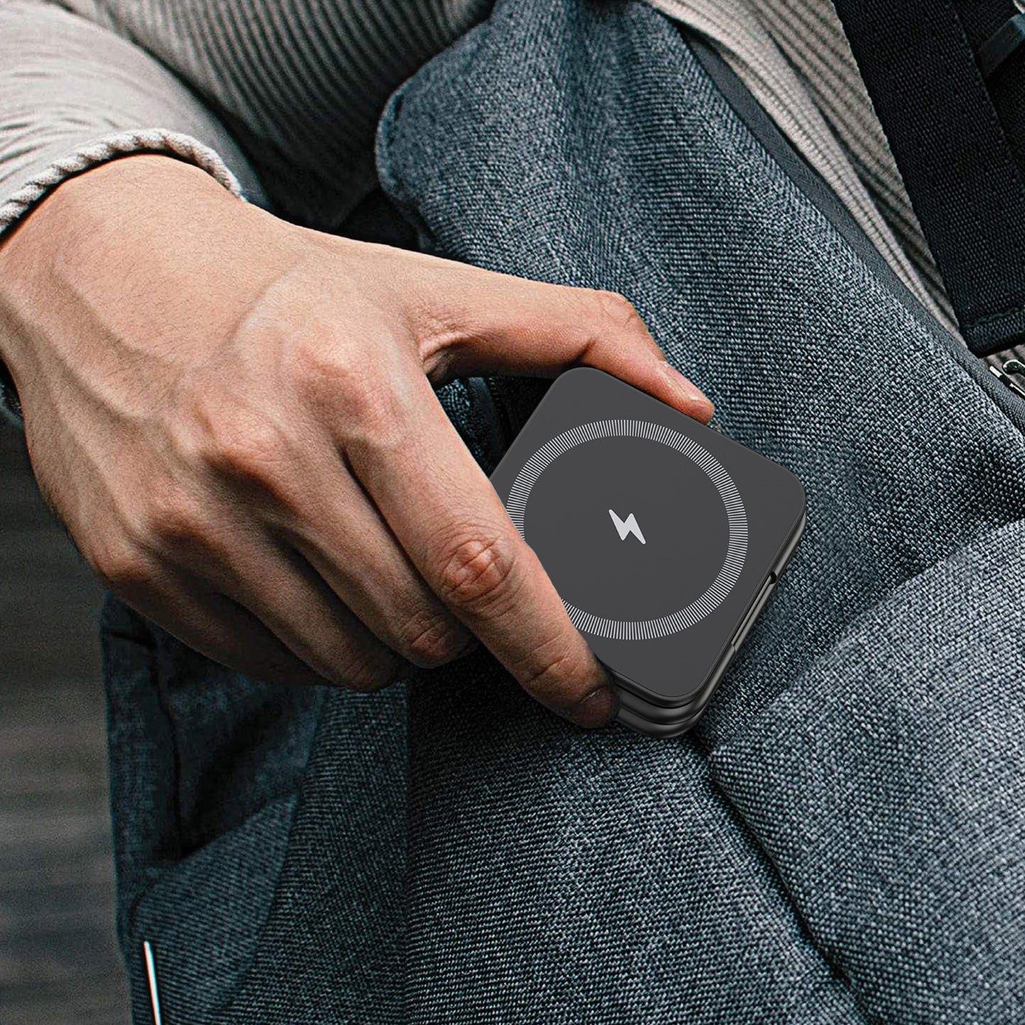 Person holding a wireless charging device in a textured jacket pocket