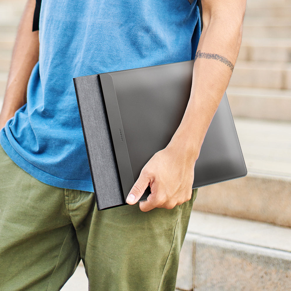 Person holding a black laptop case outdoors