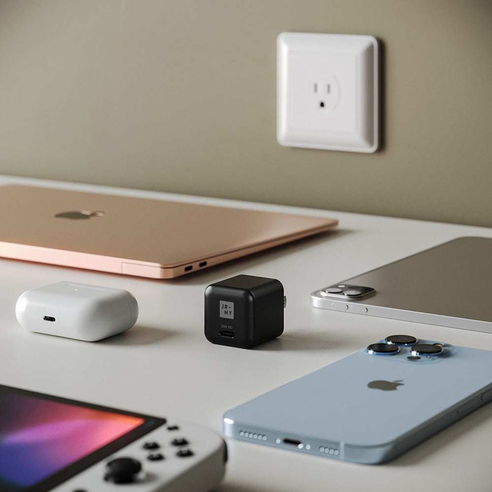Tech accessories including a laptop, phone, and power adapter on a desk.