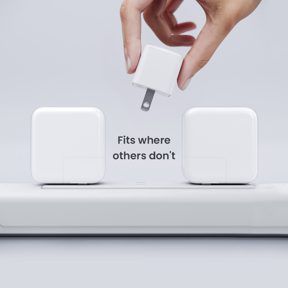 White electronic device with a plug being inserted, on a light gray background.