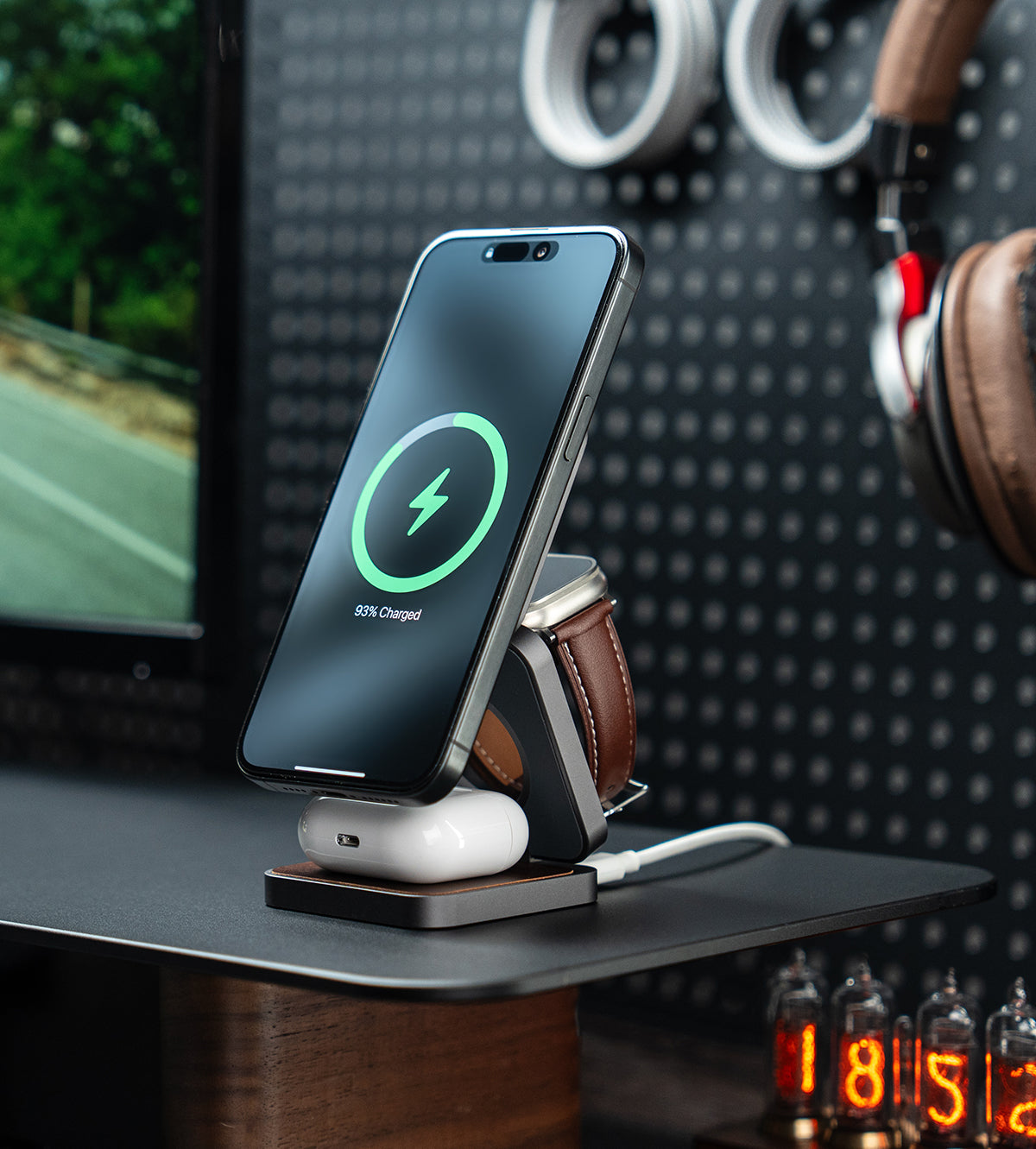 Multi-device charging stand with smartphone, smartwatch, and wireless earbuds on a desk.